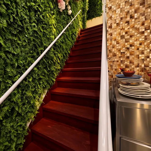 Staircase with red carpet and a white handrail beside a foliage wall
