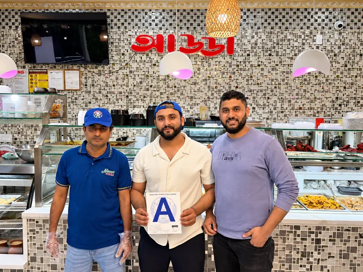 The Adda team at the counter, holding the NYC sanitary inspection grade A card
