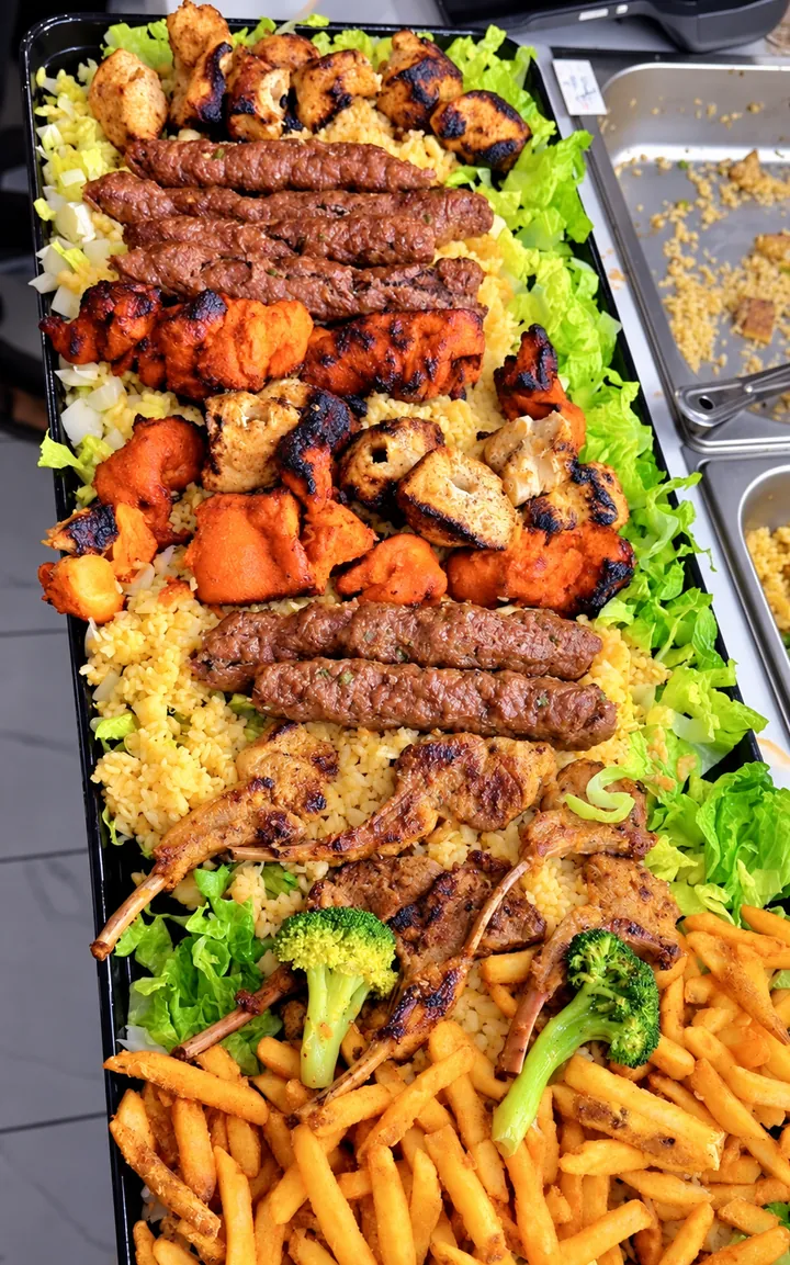 Long grill tray of seekh kababs, chicken tikka, malai boti and lamb chops over rice, with salad and spiced fries